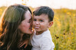 © Cavan Images - Mother snuggles multiracial son outside in flower field with love