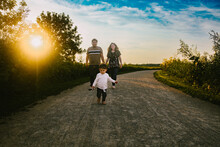 Family Walks Along A Path In Summer Outside In Nature And Sunshine