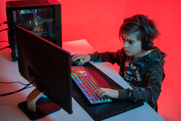 Wall Mural - Young gamer boy with headphones playing computer video game.