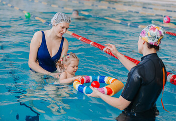 A swimming teacher teaches a kid to swim in the pool