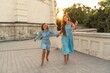 © svetograph - Mother daughter sunset. in blue dresses with flowing long hair against the backdrop of sunset. The woman hugs and presses the girl to her.