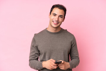 Poster - Young caucasian man isolated on pink background sending a message with the mobile