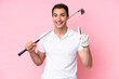 © luismolinero - Young golfer player man isolated on pink background showing and lifting a finger in sign of the best