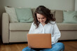 © Kristina89 - Beautiful young woman works online at home with a laptop. Home Office. Study online. Social media. Video conversation. Cozy house.