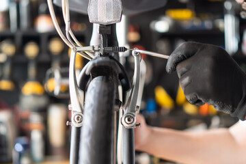 Wall Mural - Technician makes adjustments to brake on a folding bicycle working in workshop , Bicycle Repair and maintenance concept