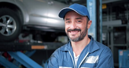 Wall Mural - Smiling face of Caucasian man car mechanic standing looking at camera at autocar