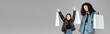 © LIGHTFIELD STUDIOS - Cheerful preteen girl holding shopping bags near mom isolated on grey, banner.