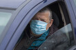 Portrait of Caucasian senior driver wearing mask while sitting inside his car
