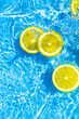 Creative summer composition made of sliced lemon in transparent blue water. Refreshment concept. Healthy refreshing drink theme. Top view