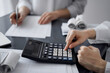 © rogerphoto - Woman accountant using a calculator and laptop computer while counting taxes for a client. Business audit and finance concepts.