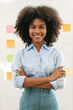 © NAMPIX - Portrait of young smiling african american woman with arms crossed standing in office.