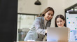 © ArLawKa - Two beautiful Asian businesswoman in conversation Exchange ideas at work Company employees working together by talking and guiding each other with papers, graphs and desk laptops.