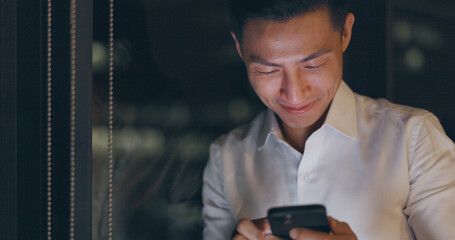 Smartphone, night and business man networking on global app, happy notification or social media chat. Smile of corporate, asian worker using phone or cellphone in dark office on digital communication