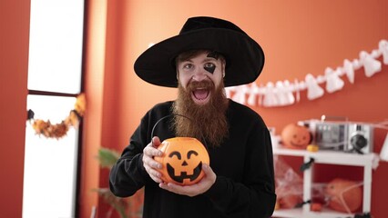 Poster - Young redhead man wearing wizard costume holding halloween pumpkin basket at home