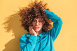 © ADDICTIVE STOCK - Charming curly haired woman touching cheek against yellow wall