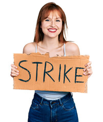 Poster - Redhead young woman holding strike banner cardboard smiling with a happy and cool smile on face. showing teeth.