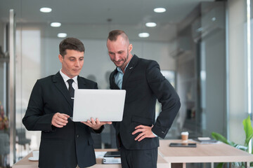 Wall Mural - Two business people talk project strategy at office meeting room. Businessman discuss project planning with colleague at modern workplace while having conversation and advice on financial data report.