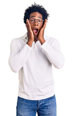 Poster - Handsome african american man with afro hair wearing casual clothes and glasses afraid and shocked, surprise and amazed expression with hands on face