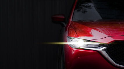 close up headlight of red car against black background.