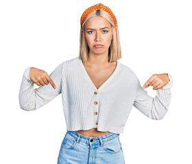 Canvas Print - Beautiful young blonde woman wearing casual white sweater pointing down looking sad and upset, indicating direction with fingers, unhappy and depressed.