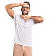 Young hispanic man wearing casual clothes and glasses smiling cheerful playing peek a boo with hands showing face. surprised and exited