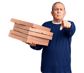 Wall Mural - Senior handsome man holding pizza boxes pointing with finger to the camera and to you, confident gesture looking serious