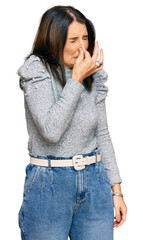 Sticker - Middle age brunette woman wearing casual clothes smelling something stinky and disgusting, intolerable smell, holding breath with fingers on nose. bad smell