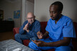 A doctor during a home visit with his patient uses the digital tablet.