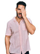 © Krakenimages.com - Hispanic man with beard wearing casual shirt covering one eye with hand, confident smile on face and surprise emotion.