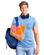 © Krakenimages.com - Young handsome man wearing student backpack and headphones holding book and america flag looking positive and happy standing and smiling with a confident smile showing teeth