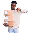 Young african american man holding delivery package with angry face, negative sign showing dislike with thumbs down, rejection concept
