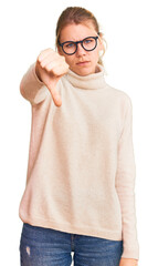 Wall Mural - Young beautiful blonde woman wearing turtleneck sweater and glasses looking unhappy and angry showing rejection and negative with thumbs down gesture. bad expression.