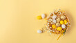 Easter candy chocolate eggs and almond sweets lying in a bird's nest decorated with flowers and feathers on a yellow background. Top view long banner. Happy Easter concept.