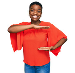 Sticker - Young african american woman wearing casual clothes gesturing with hands showing big and large size sign, measure symbol. smiling looking at the camera. measuring concept.