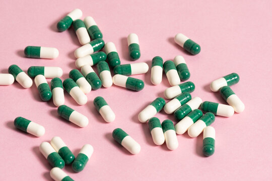 Píldoras de color blanco y verde sobre fondo rosado - white and green pills on pink background