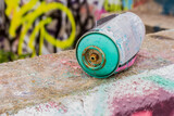 Fototapeta Młodzieżowe - A discarded spray paint can sits in a graffiti covered urban area, urban decay, vandalism.