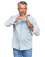 Poster - Middle age grey-haired man wearing casual clothes doing time out gesture with hands, frustrated and serious face