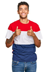 Wall Mural - Young handsome african american man wearing casual clothes success sign doing positive gesture with hand, thumbs up smiling and happy. cheerful expression and winner gesture.