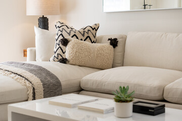 Modern living room details of large comfy sofa with pillows, blanket, and coffee table.