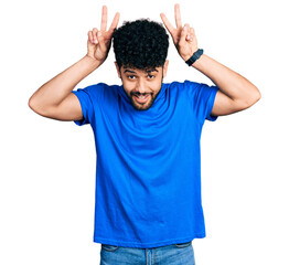 Canvas Print - Young arab man with beard wearing casual blue t shirt posing funny and crazy with fingers on head as bunny ears, smiling cheerful