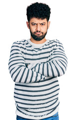 Poster - Young arab man with beard wearing casual striped sweater skeptic and nervous, disapproving expression on face with crossed arms. negative person.