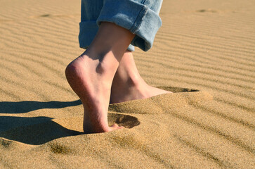 Barefoot girl in jeans walking in the sands on the coast