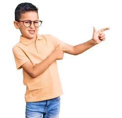 Wall Mural - Little cute boy kid wearing casual clothes and glasses smiling and looking at the camera pointing with two hands and fingers to the side.