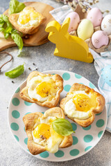 Wall Mural - Easter breakfast idea. Scrambled eggs in puff pastry with cheese and bacon on a stone background.
