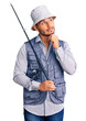 © Krakenimages.com - Handsome latin american young man wearing fisherman equipment serious face thinking about question with hand on chin, thoughtful about confusing idea