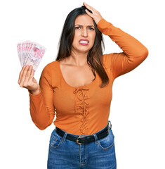 Poster - Beautiful hispanic woman holding 50 turkish lira banknotes stressed and frustrated with hand on head, surprised and angry face