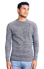 Canvas Print - Hispanic handsome young man wearing casual sweater smiling looking to the side and staring away thinking.