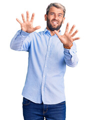 Sticker - Young handsome blond man wearing elegant shirt afraid and terrified with fear expression stop gesture with hands, shouting in shock. panic concept.