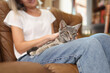 © megaflopp - Female sitting on sofa and petting grey cat