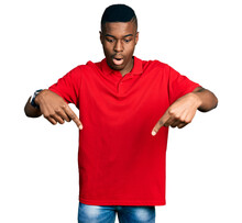 Young African American Man Wearing Casual Red T Shirt Pointing Down With Fingers Showing Advertisement, Surprised Face And Open Mouth